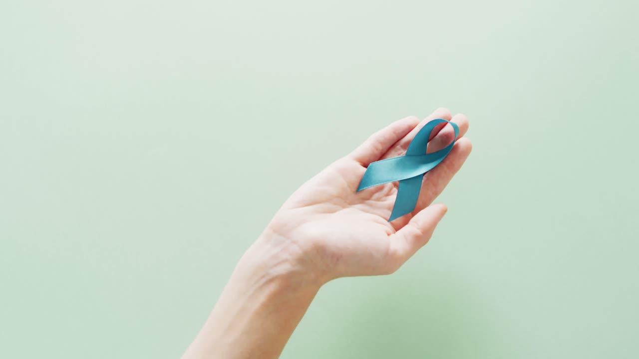 녹색 배경에 파란색 난소암 인식 리본을 들고 있는 손의 비디오