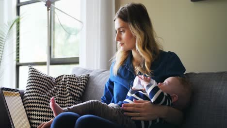 Mother-using-laptop-while-feeding-her-baby-4k