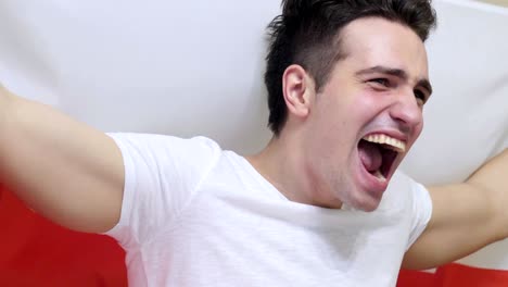 polish young man celebrating while holding the flag of poland in slow motion