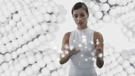mujer usando una pantalla interactiva transparente sobre bolas blancas pulsantes