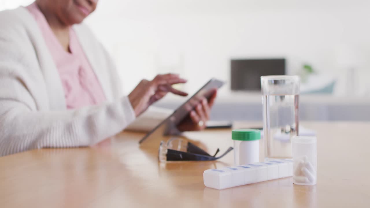 retrato de una mujer afroamericana mayor sentada en una mesa, usando una tableta