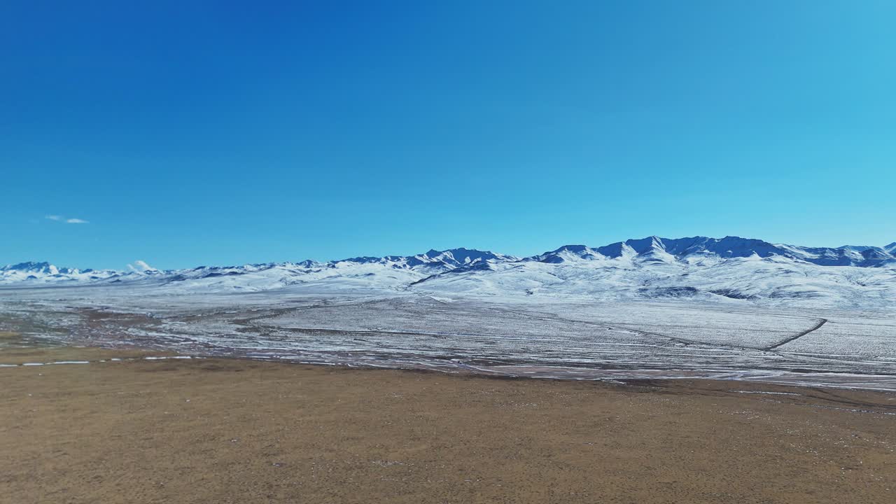 Qilian Grassland, Xining, Qinghai-provinsen, Kina – En enorm, snødekt slette strekker seg mot fjerne fjellrygger under en klar, dypblå himmel – Push In Shot