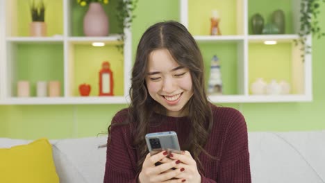 아름답고 매력적인 아시아 젊은 여성이 전화로 문자 메시지를 보내고 있습니다.