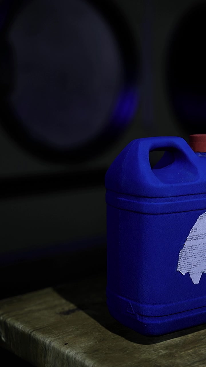 Contenedor con líquido de color azul sobre una superficie de madera con luz tenue