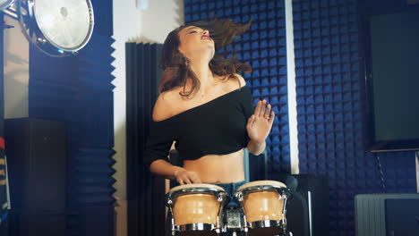 una mujer tocando la batería en un estudio de grabación profesional.