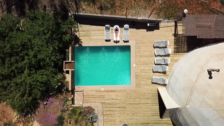 Drone flying up over Geodesic dome in Chilean desert with a pool