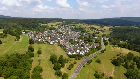 vuelo con un drone dji phantom 4 hacia un pueblo rural alemán ubicado en un hermoso bosque, colinas y área de campo
