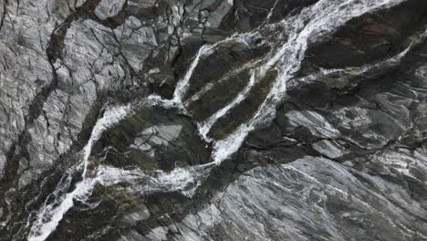 waterfall on a steep rock face in the mountains from above, norway, europe, drone