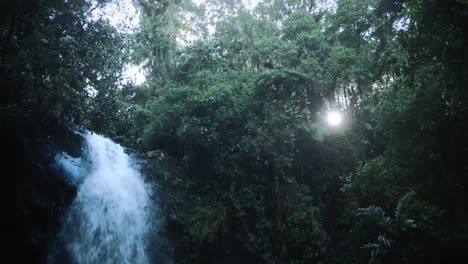 Una-Cascada-Y-El-Sol-Brilla-A-Través-De-Los-árboles-En-Una-Selva-Tropical