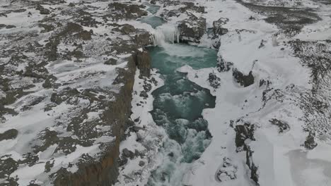 Vista-Aérea-Sobre-La-Cascada-De-Aldeyjarfoss-En-El-Paisaje-Nevado-De-Islandia