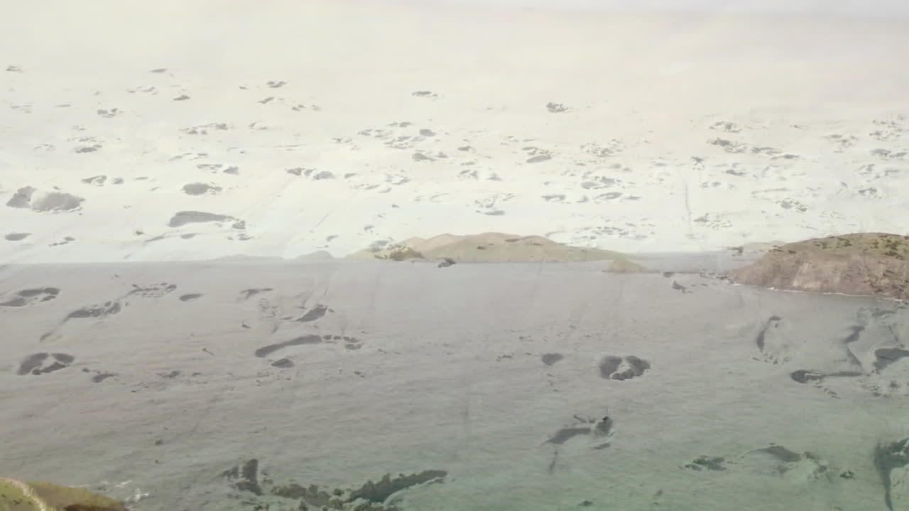 Snow-covered landscape meeting rocky shoreline with calm water in serene animation