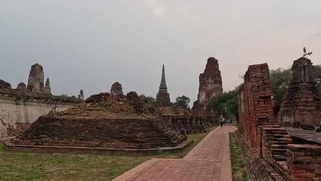 explore the weathered brick ruins and pathway surrounded by lush greenery and historical structures.