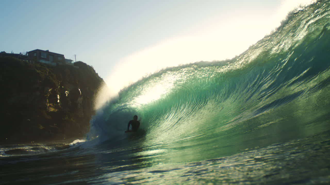 Backlit surfer rides through heavy tube at Whaley Wedge with glowing lip and flying mist