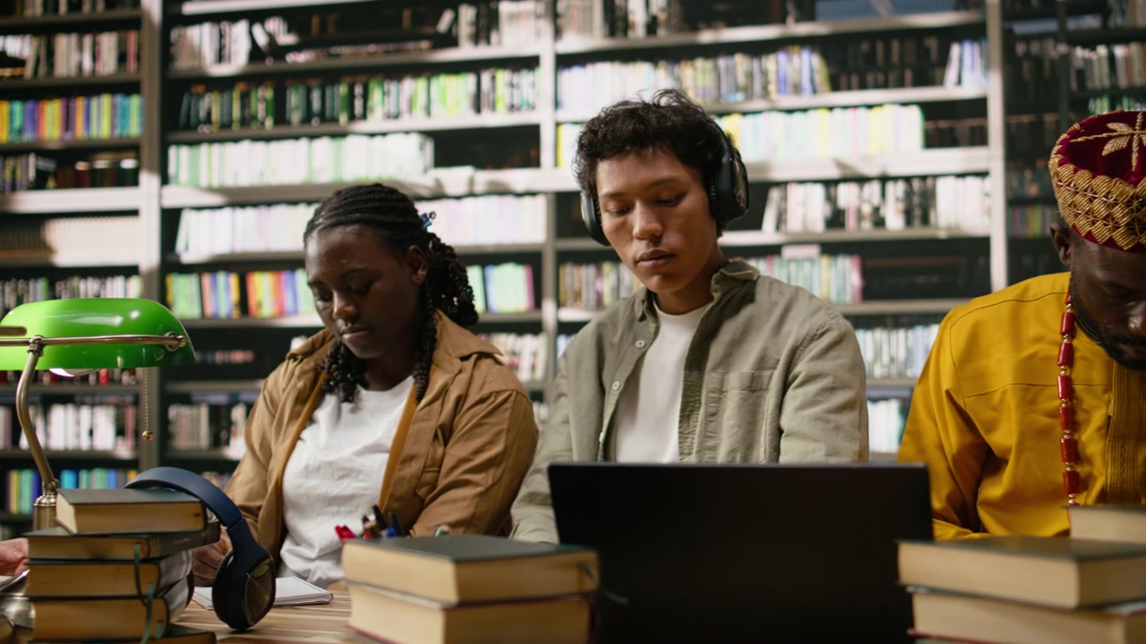 Students reviewing academic work on laptop with mature colleague