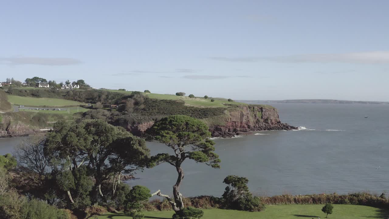 Ripresa aerea che si alza dal bellissimo parco verde di Dunmore East, con scogliere marine in lontananza.