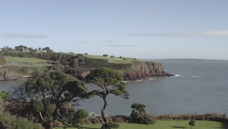 aerial rises from beautiful green dunmore east park, sea cliffs beyond