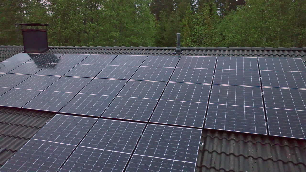 드론이 집 지붕 위의 광전지 패널을 돌고, 다채로운 여름 해가 지는 모습