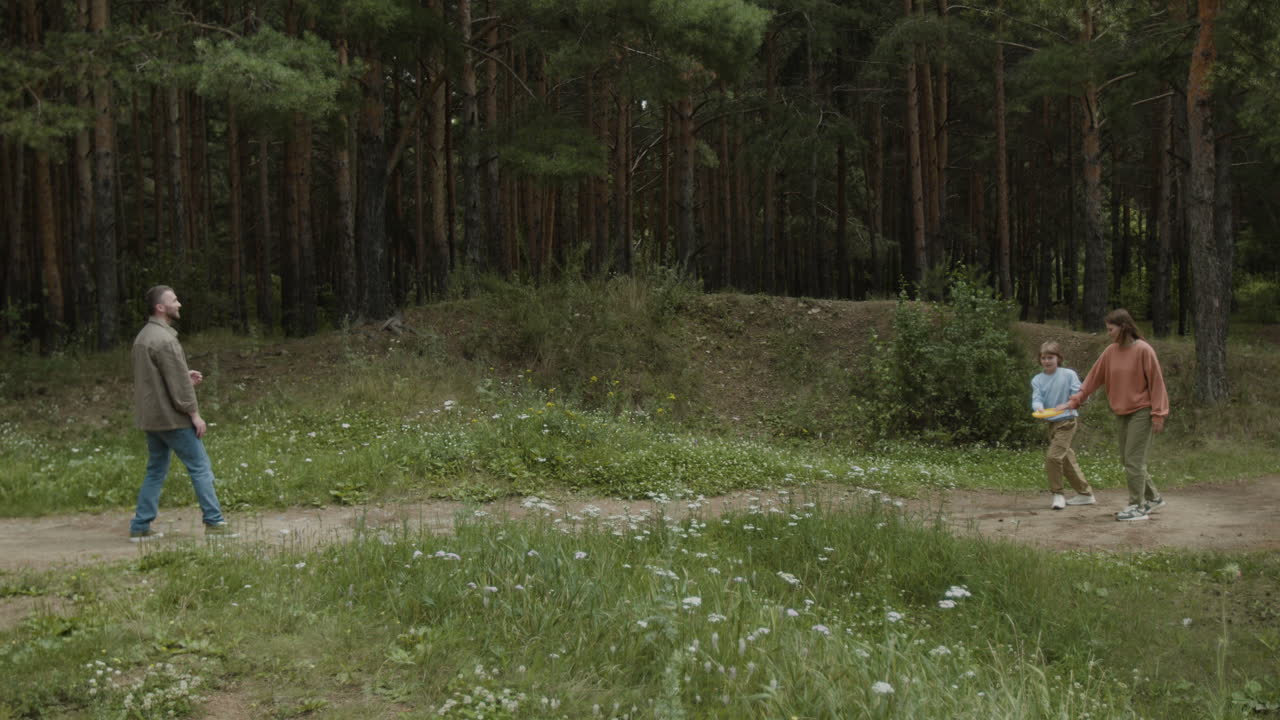 Family playing frisbee in the forest