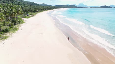 man walking on nacpan beach alone, drone reveal seaside, tropical travel destination.