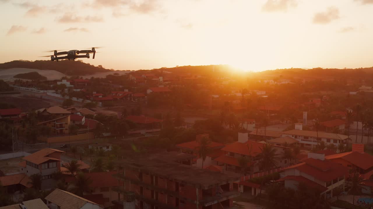 Drone flying over a cityscape at sunset