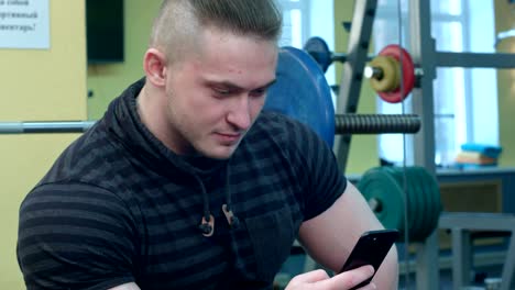 man using smartphone in the gym after training