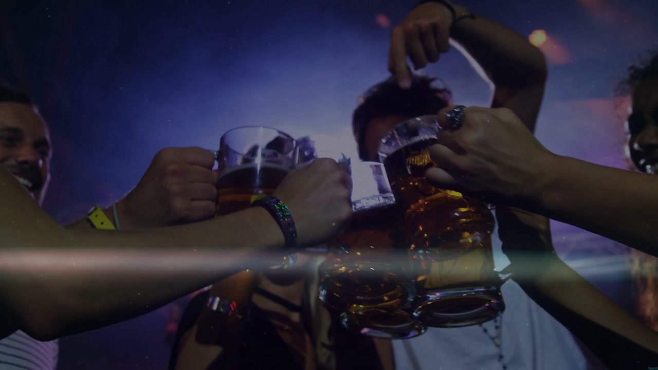 Amici che alzano boccali di birra per brindare, facendoli tintinnare davanti alla telecamera, celebrando il locale con bagliori dell'obiettivo.