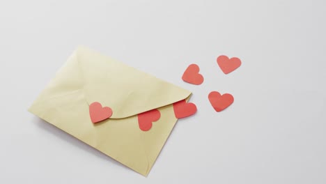 paper hearts and envelope on pink background at valentine's day