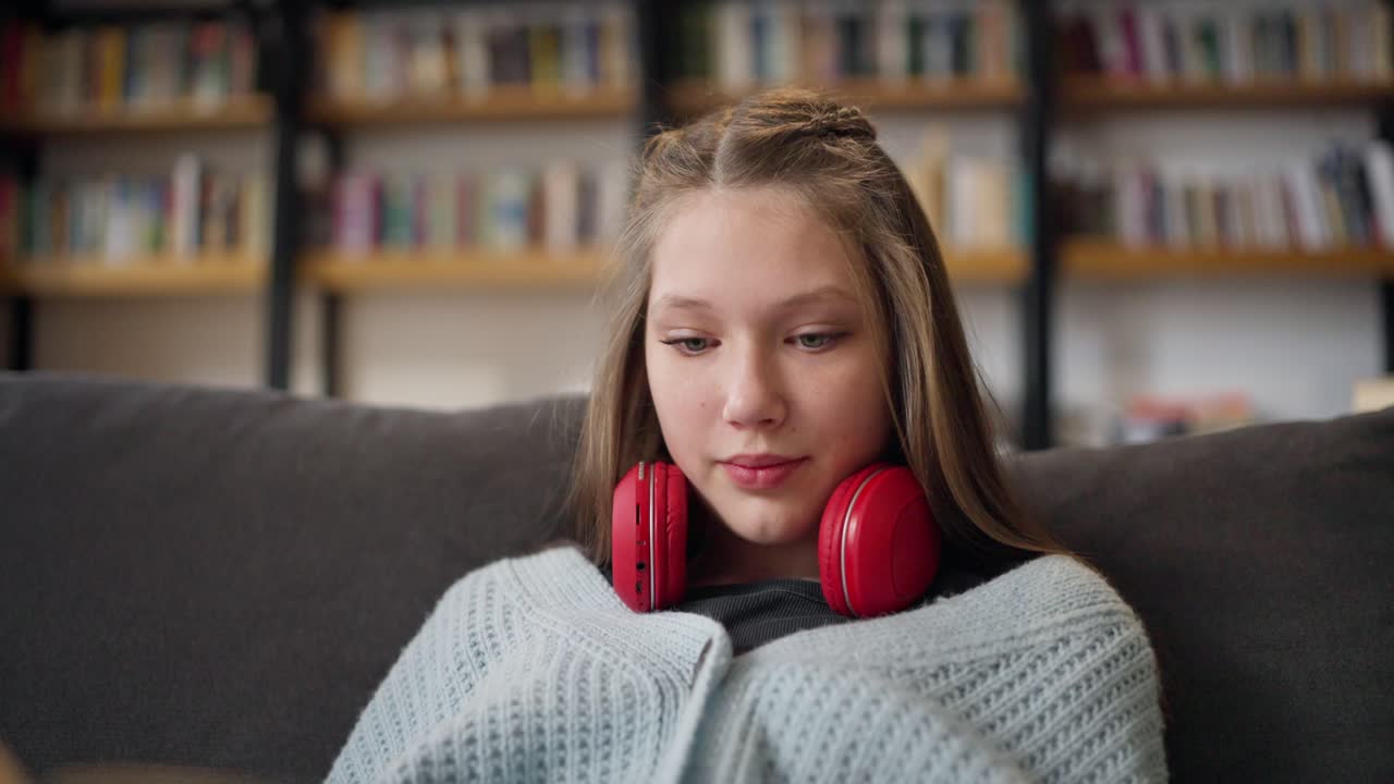 Teenage girl studying on a sofa in a library.