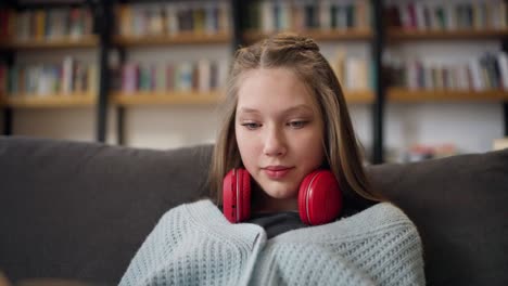 teenage girl studying on a sofa in a library.