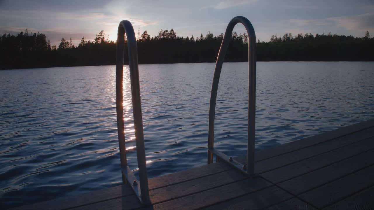 Tikkaat uimalaiturilla auringonlaskun aikaan ruotsalaisella järvellä