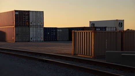shipping containers and railroad tracks at sunset