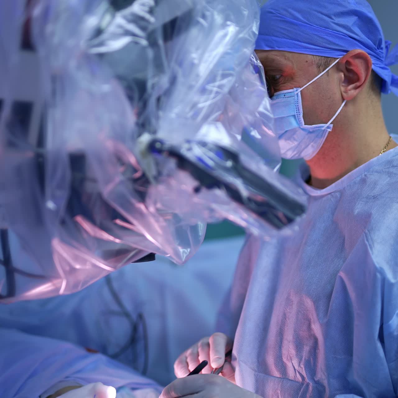 Doctor performing accurate surgery looking through the microscope. Technological equipment is covered with plastic