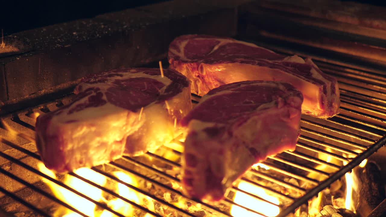 tre grosse bistecche grigliate su una griglia a fuoco aperto dal fuoco di legna