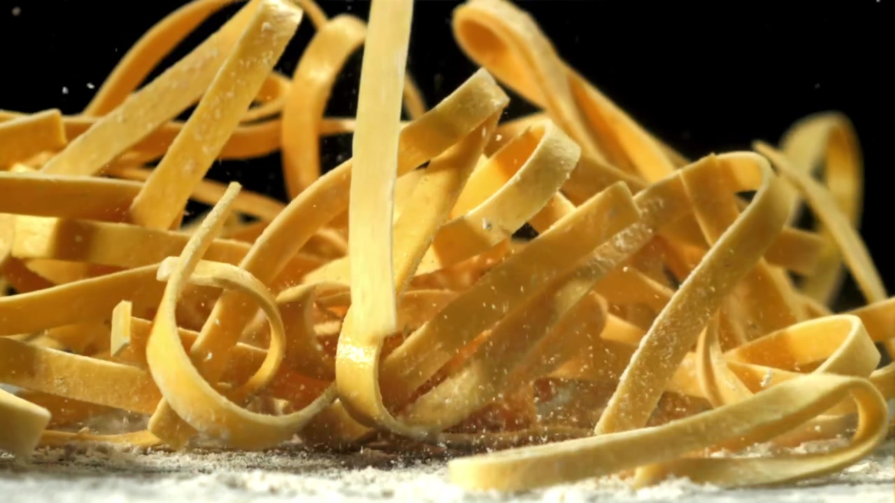 Pasta tagliatelle cruda che cade sulla farina al rallentatore