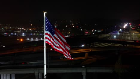 national flag of america waving with the wind with the highway in the background at night