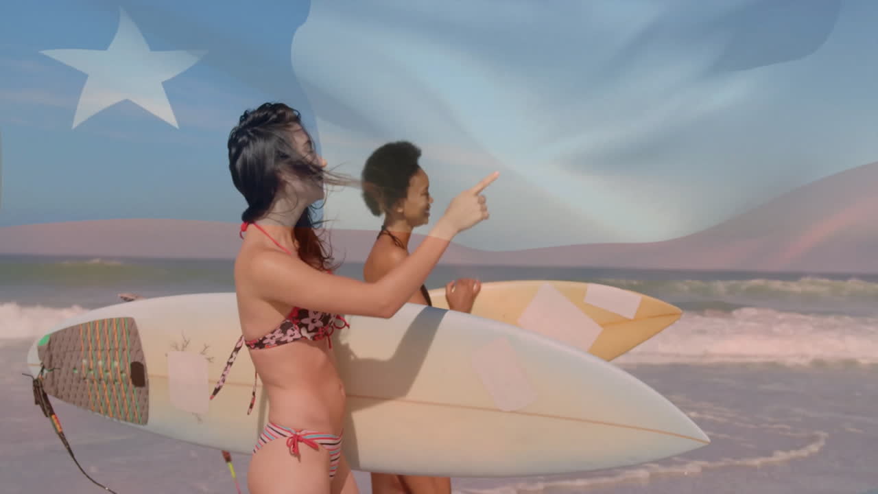 Holding surfboards on beach, two women with animation flag overlay in background