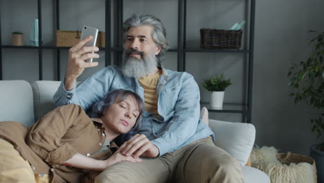 couple relaxing on sofa taking a selfie