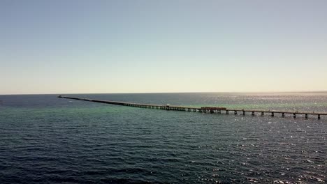 stunning aerial view of a long pier extending into the calm ocean