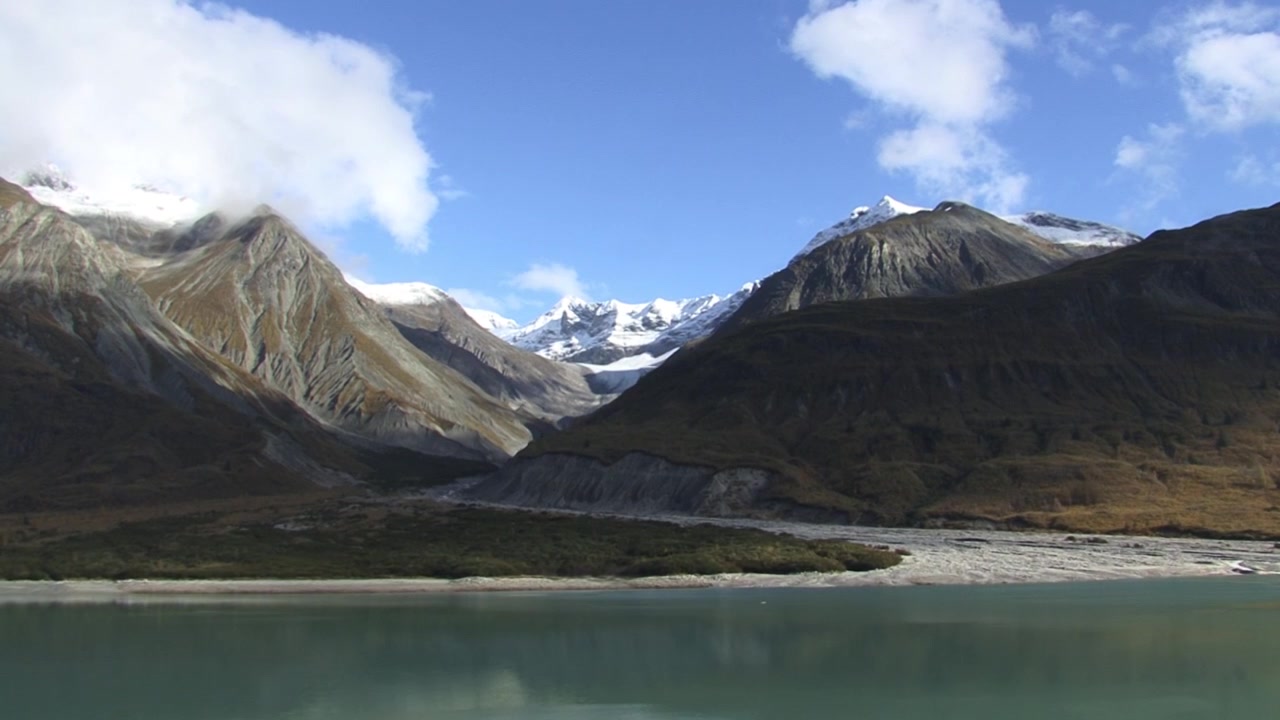 Montagne della Baia dei Ghiacciai, Alaska, in una giornata di sole con cielo azzurro e nuvole bianche e soffici. Splendida ripresa paesaggistica delle montagne e delle acque della baia.