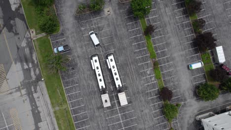 Aerial-view-above-two-tour-buses-with-trailers-on-a-parking-lot---rotating,-top-down,-drone-shot