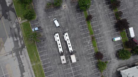 aerial view above two tour buses with trailers on a parking lot - rotating, top down, drone shot