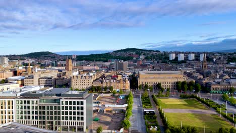 high-altitude drone footage smoothly pans across inverness, scotland, revealing urban architecture, green spaces, and distant hills under bright natural daylight