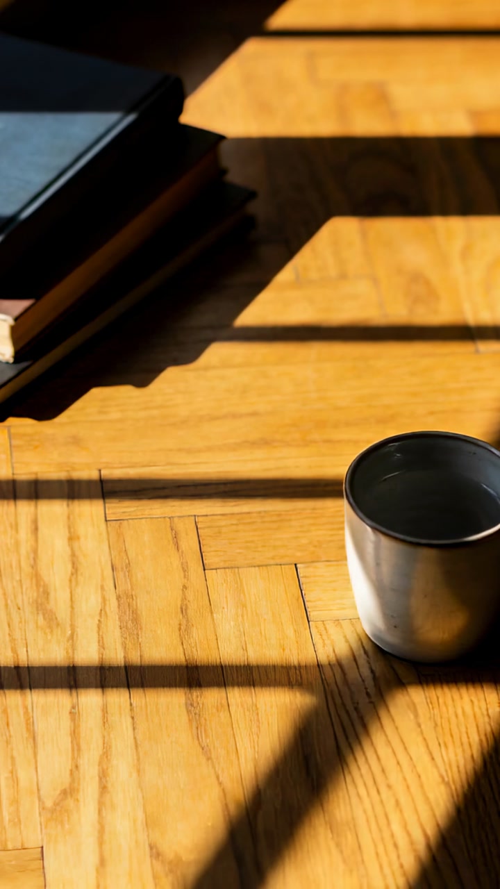 Vertical video: Sunlight shifting, window grid shadows crossing ceramic mug on parquet, copy space