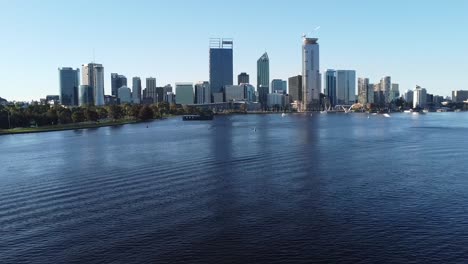 drone shot descending down to sanding beach bank of swan river with skyline of perth, western australia from and south perth foreshore