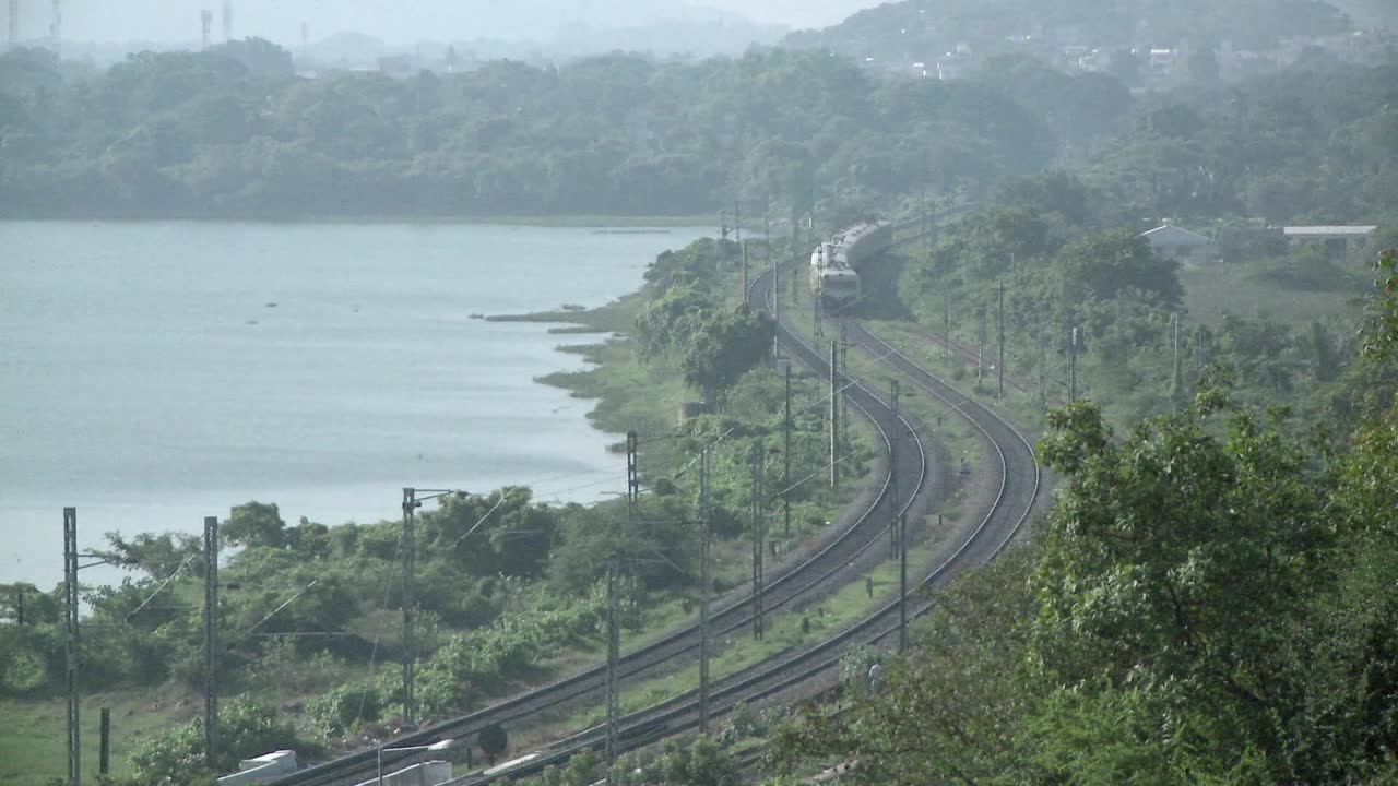 un tren que se aproxima recorre una ruta rural cerca de un lago