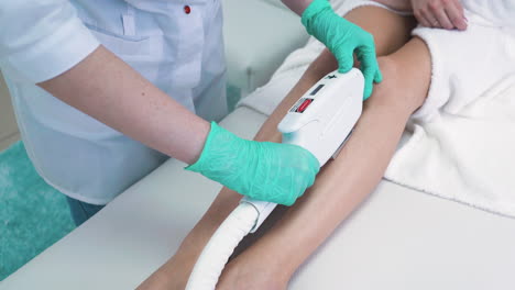 el dermatólogo hace un procedimiento de depilación láser en la clínica.