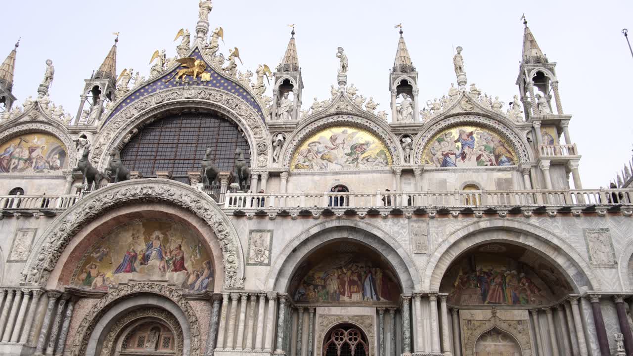 Frontal pan across ornate historic Saint Marks Basilica on foggy grey day