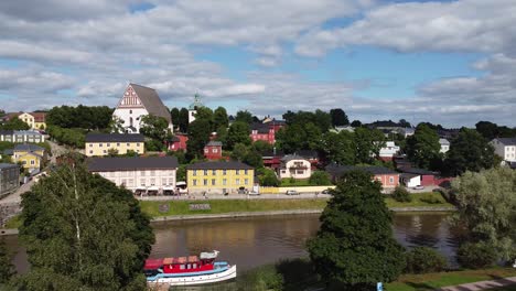 Luftschwenkaufnahme-Der-Idyllischen-Porvoo-Stadt-Mit-Bunten-Häusern,-Porvoonjoki-Fluss-Und-Andockboot-An-Sonnigen-Tagen,-Finnland