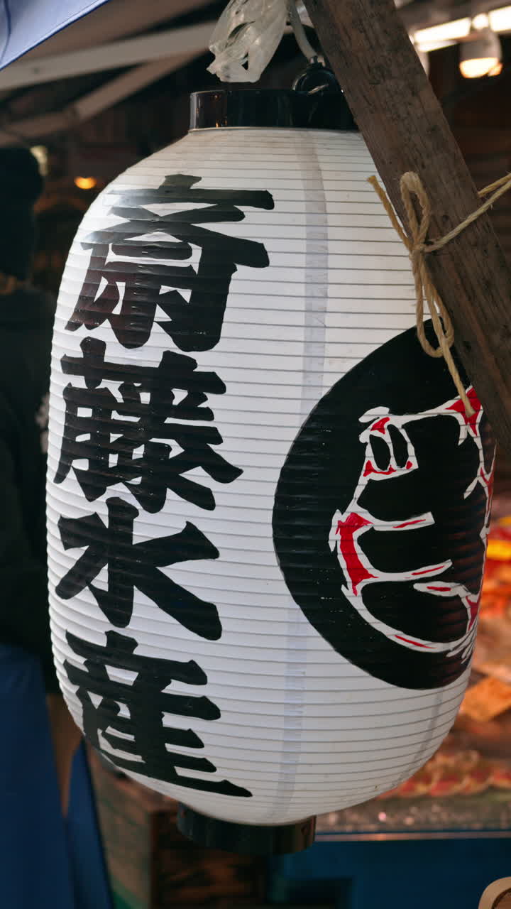 Close up of a white paper lantern at the Tsukiji Fish Market in Japan. Vertical. Translation:"Saito Suisan - shop name"