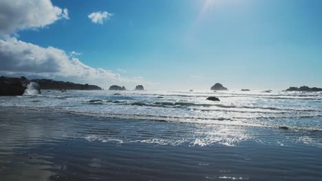 crashing waves spread and glide across bandon oregon beach, strong midday sun